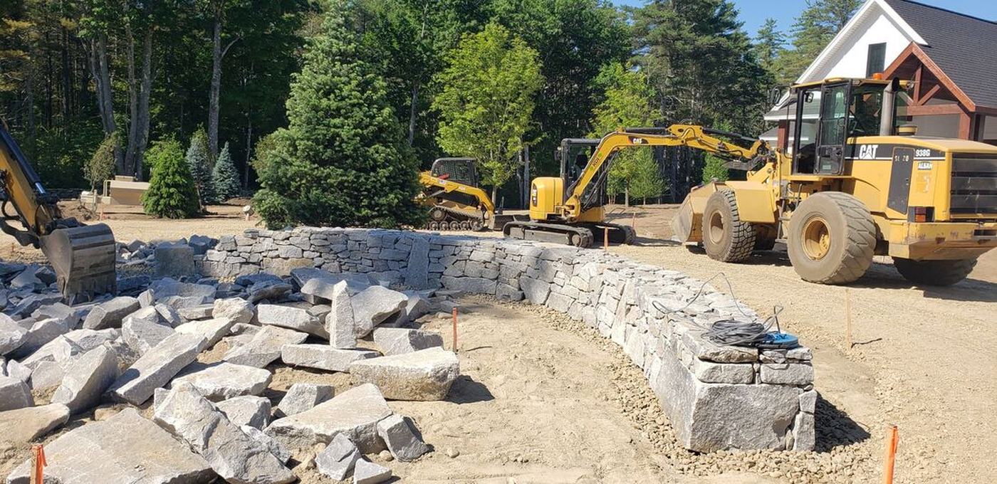 Granite wall construction in progress with equipment